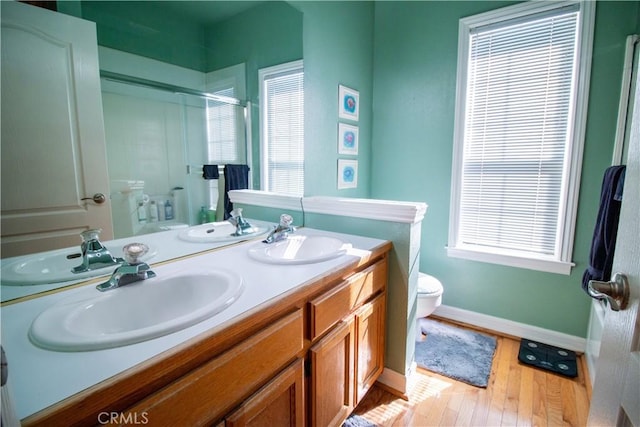 bathroom with vanity, a shower with shower door, toilet, and plenty of natural light