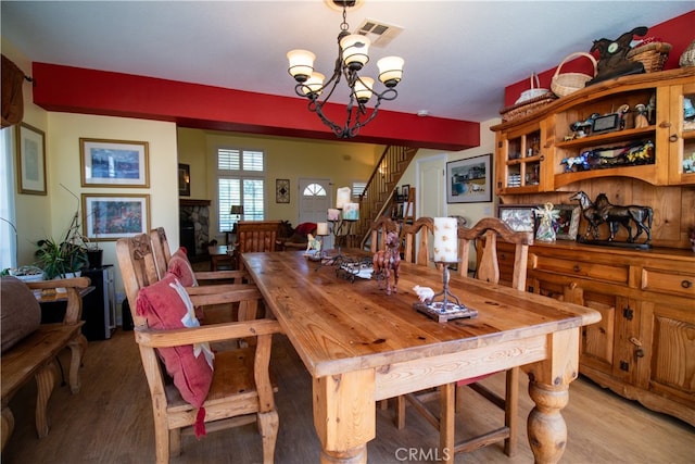 dining space with light wood-type flooring, a stone fireplace, and a chandelier