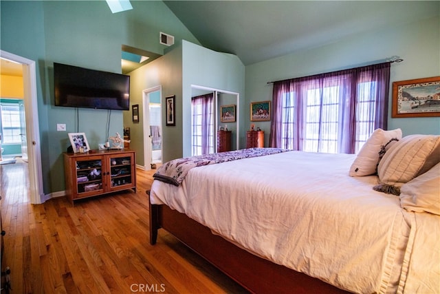 bedroom featuring wood-type flooring, lofted ceiling, and multiple windows