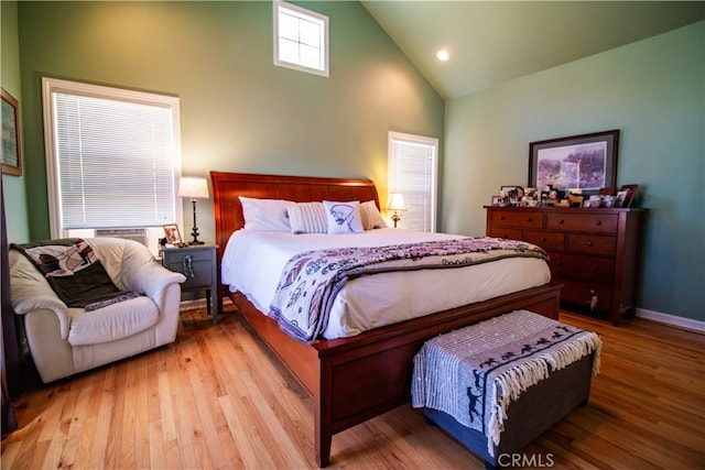 bedroom featuring high vaulted ceiling, cooling unit, and light hardwood / wood-style floors