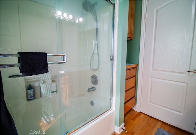 bathroom with enclosed tub / shower combo, vanity, and wood-type flooring