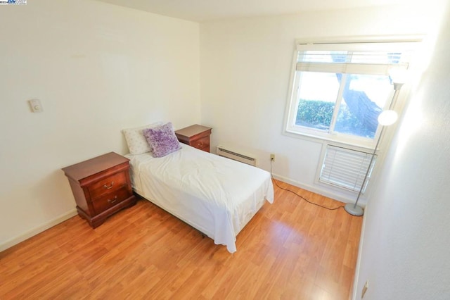 bedroom featuring baseboard heating and hardwood / wood-style flooring