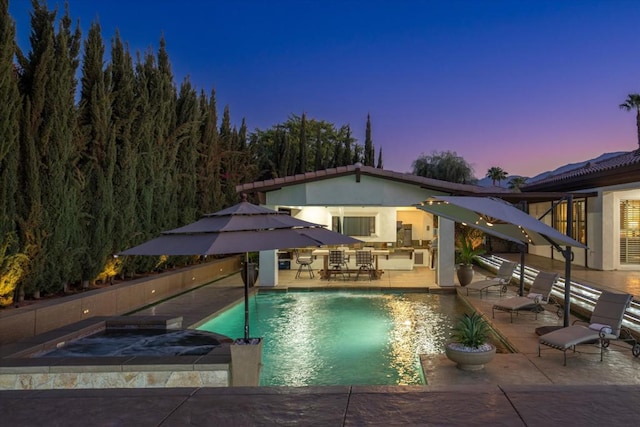 pool at dusk featuring a water slide, a hot tub, and a patio