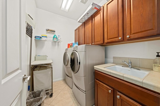 laundry room with sink, cabinets, washing machine and clothes dryer, and light tile patterned floors