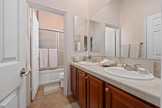 full bathroom with toilet, tile patterned floors, vanity, and bath / shower combo with glass door