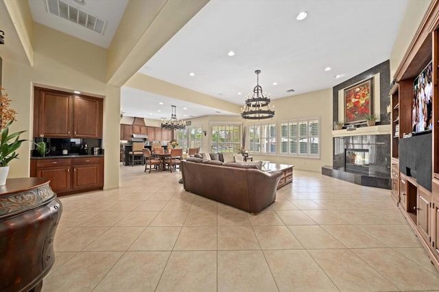 tiled living room with a tiled fireplace and a notable chandelier