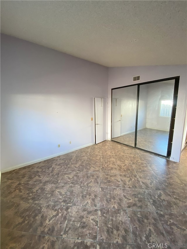 unfurnished bedroom featuring a textured ceiling, a closet, and lofted ceiling