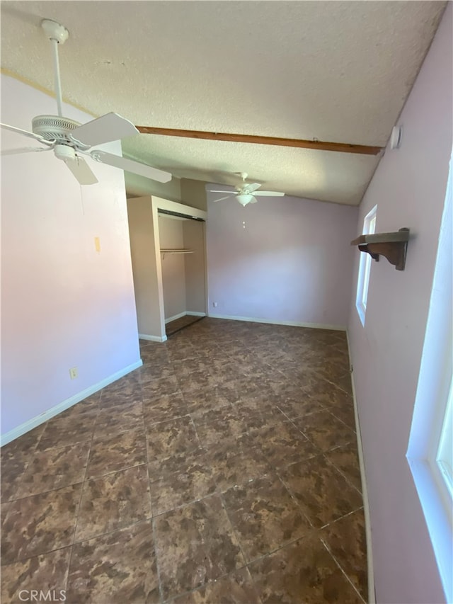 unfurnished room with ceiling fan, a textured ceiling, and lofted ceiling with beams