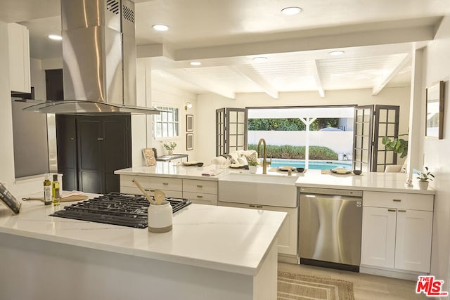 kitchen with light stone countertops, appliances with stainless steel finishes, island range hood, beamed ceiling, and white cabinets