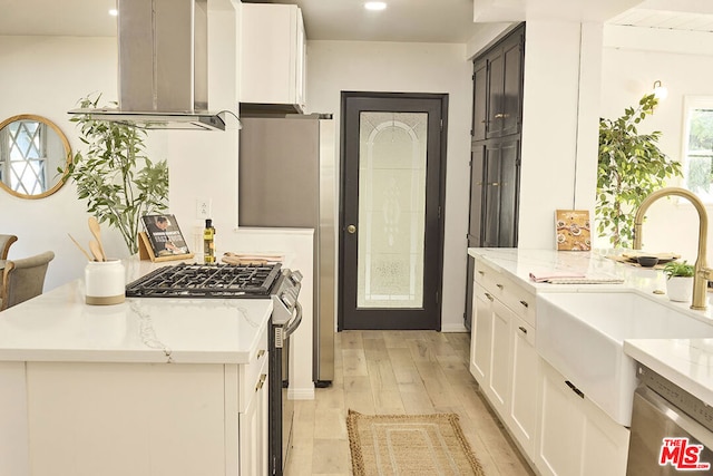 kitchen featuring white cabinets, light wood-type flooring, stainless steel appliances, and range hood