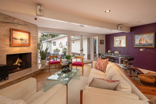 living room with light hardwood / wood-style flooring, a high end fireplace, and french doors