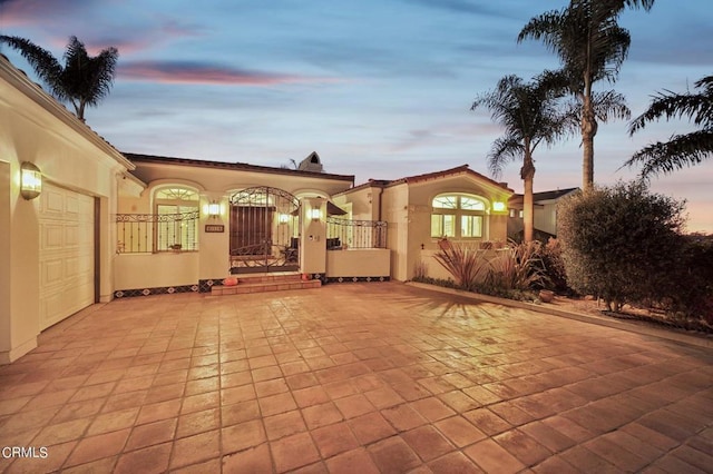 view of front of home with decorative driveway, an attached garage, and stucco siding