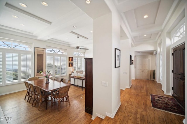 dining space featuring light wood finished floors, beamed ceiling, and coffered ceiling