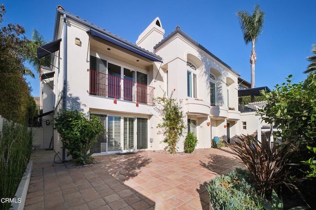rear view of property featuring stucco siding, a balcony, and a patio area