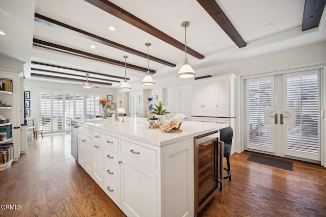 kitchen featuring beverage cooler, stainless steel dishwasher, dark wood-style floors, a breakfast bar area, and white cabinets