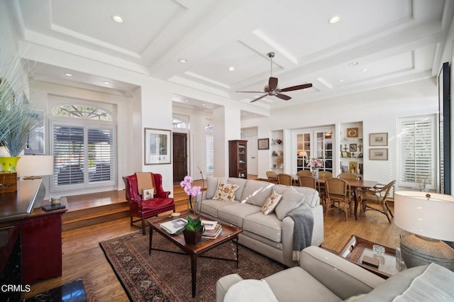 living room with ceiling fan, beam ceiling, coffered ceiling, and wood finished floors