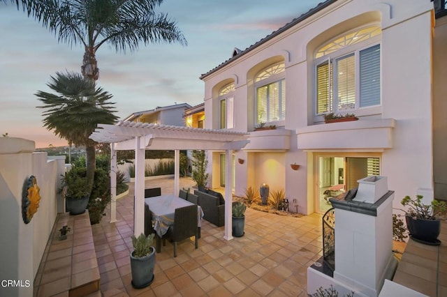 patio terrace at dusk with outdoor lounge area, a pergola, and fence