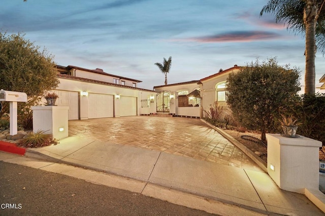 mediterranean / spanish home with decorative driveway, a garage, and stucco siding