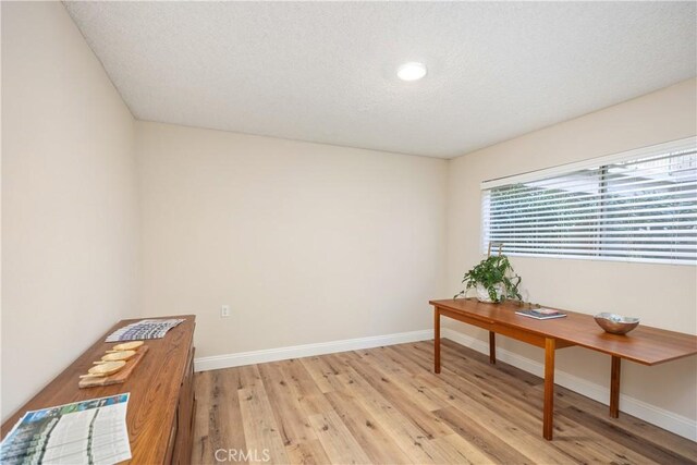 office area with light hardwood / wood-style floors and a textured ceiling