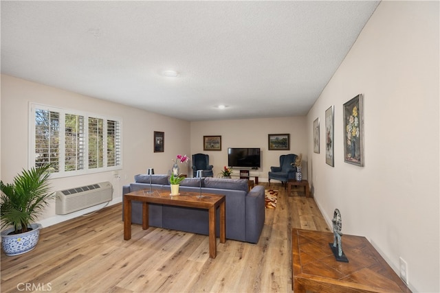 living room featuring light wood-type flooring, a textured ceiling, and a wall mounted AC