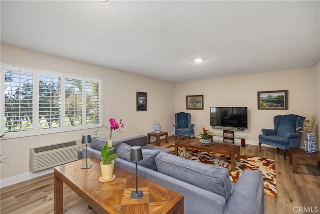 living room featuring a textured ceiling, light wood-type flooring, and a wall mounted air conditioner