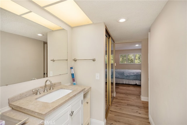 bathroom with wood-type flooring, vanity, and a textured ceiling