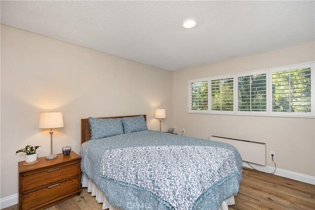 bedroom featuring a textured ceiling, radiator, and hardwood / wood-style floors