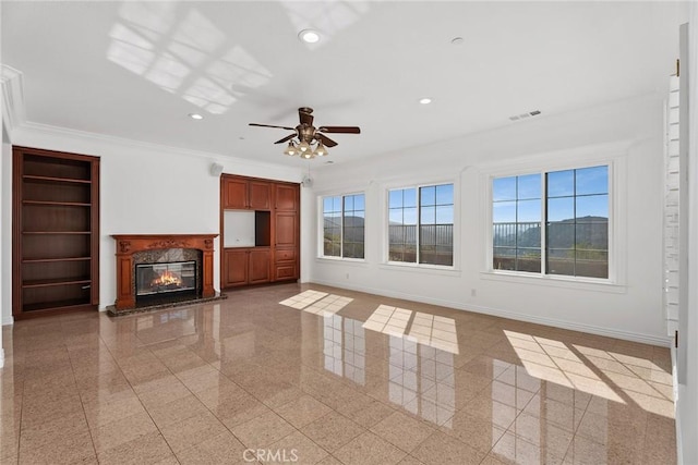 unfurnished living room with ceiling fan, a high end fireplace, and ornamental molding