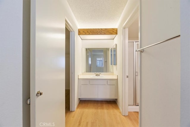 hallway featuring light wood-type flooring, a textured ceiling, and sink