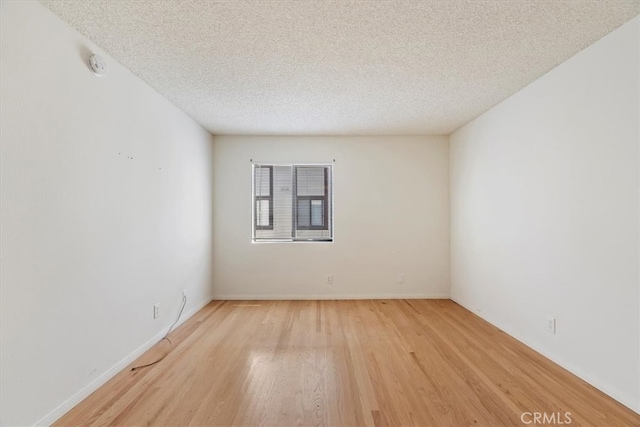 unfurnished room with light wood-type flooring and a textured ceiling