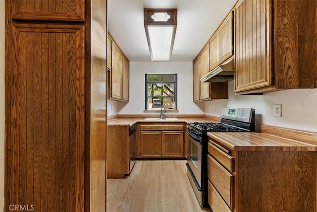 kitchen with butcher block countertops, stainless steel appliances, light wood-type flooring, and sink