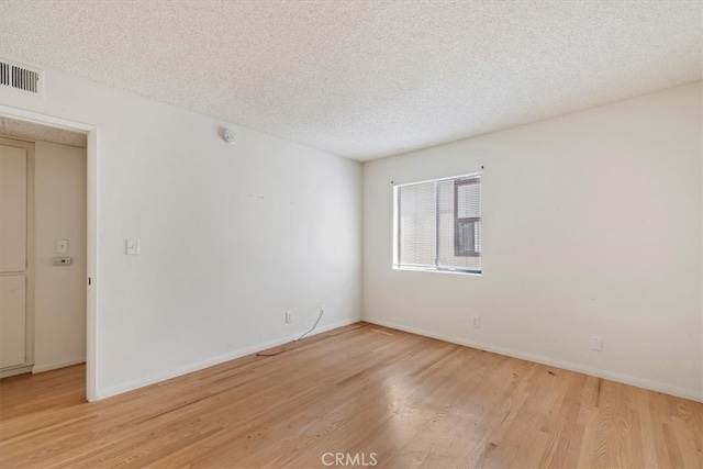 spare room featuring light wood-type flooring and a textured ceiling