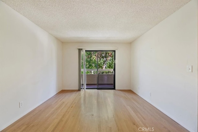 unfurnished room with light hardwood / wood-style flooring and a textured ceiling