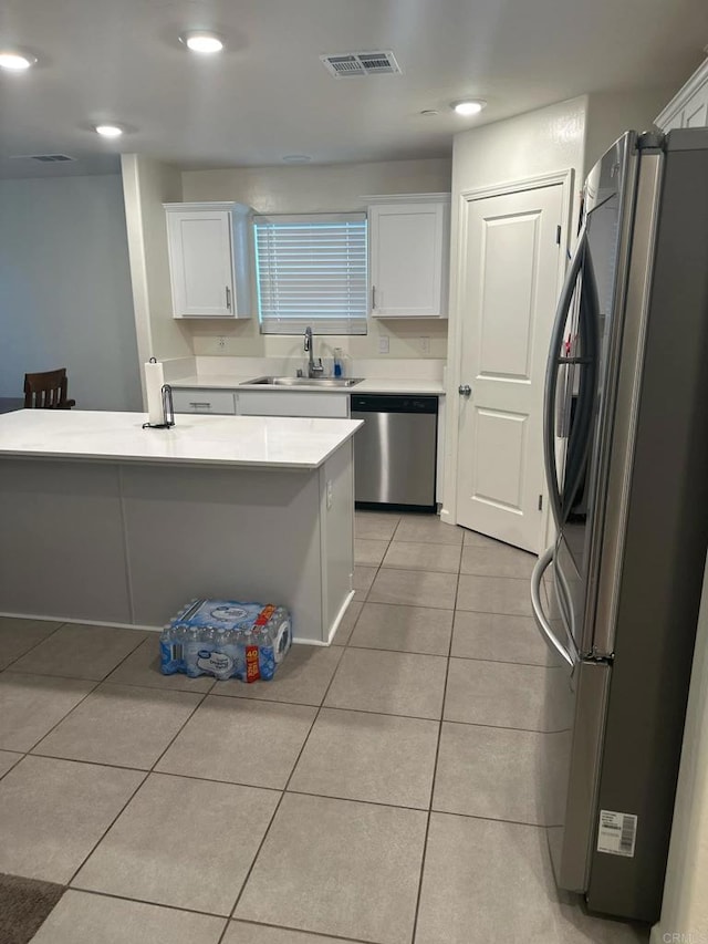 kitchen with sink, light tile patterned floors, stainless steel appliances, and white cabinets