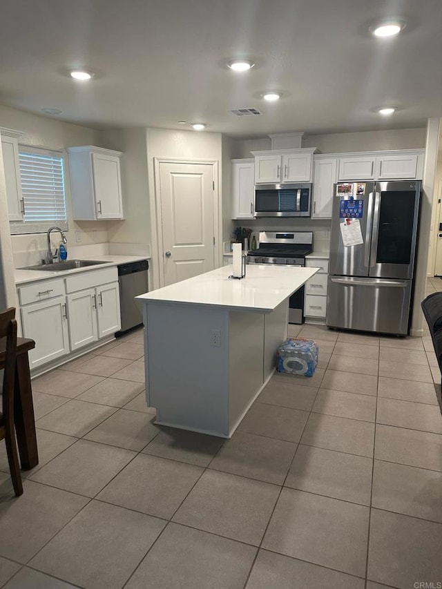 kitchen with white cabinets, light tile patterned flooring, sink, stainless steel appliances, and a center island