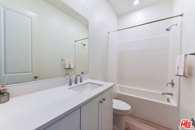 full bathroom featuring shower / bathtub combination with curtain, hardwood / wood-style flooring, vanity, and toilet