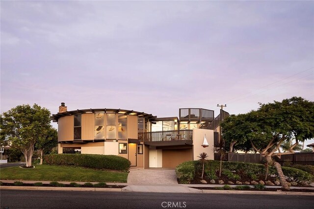 view of front of house with a balcony and a lawn