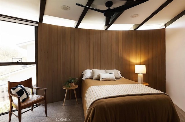 bedroom featuring ceiling fan, multiple windows, carpet flooring, and wooden walls