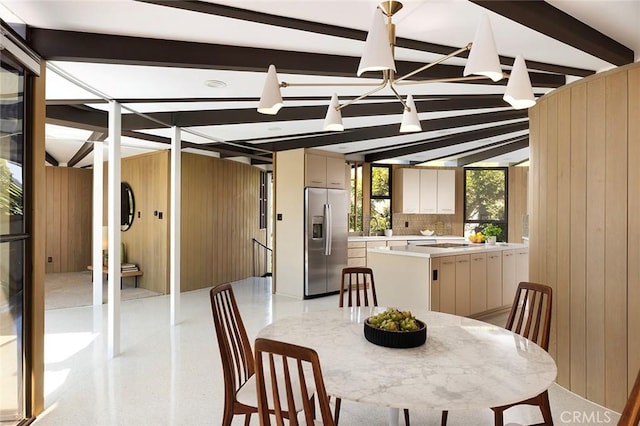 dining area with wood walls and lofted ceiling with beams