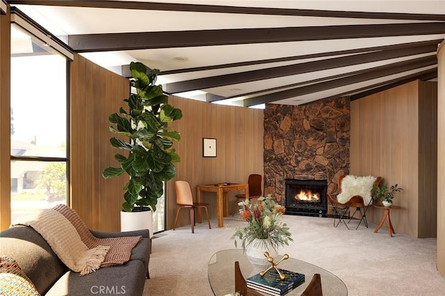 carpeted living room featuring a stone fireplace, wooden walls, and lofted ceiling with beams