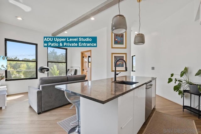 kitchen featuring sink, white cabinets, beam ceiling, hanging light fixtures, and light hardwood / wood-style flooring