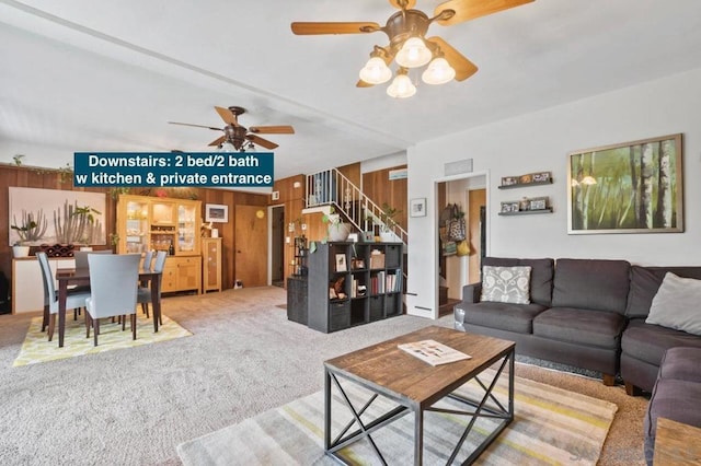 carpeted living room with ceiling fan and wood walls