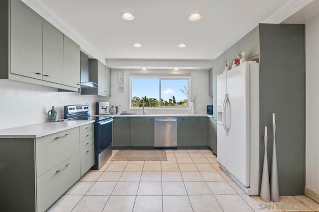 kitchen with gray cabinets, appliances with stainless steel finishes, wall chimney exhaust hood, and light tile patterned floors