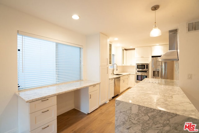 kitchen with white cabinets, ventilation hood, sink, hanging light fixtures, and stainless steel appliances