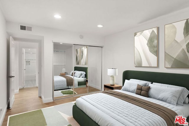 bedroom with light wood-type flooring and a closet