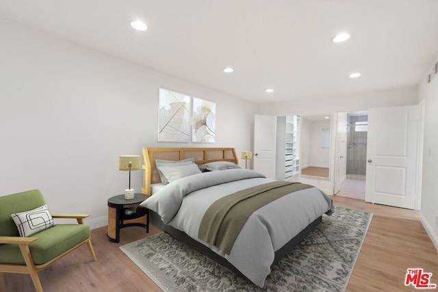 bedroom with hardwood / wood-style floors and ensuite bathroom