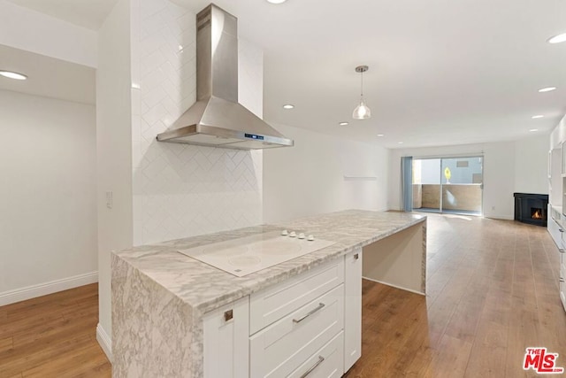 kitchen with white cabinetry, hanging light fixtures, wall chimney range hood, white electric cooktop, and light wood-type flooring