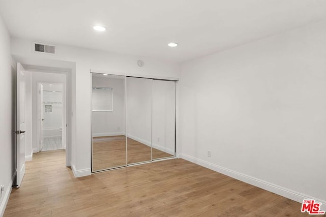 unfurnished bedroom with light wood-type flooring and a closet