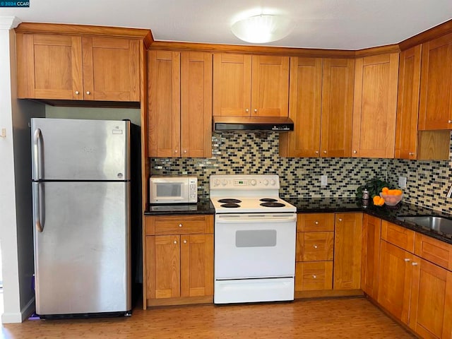 kitchen featuring light hardwood / wood-style flooring, white appliances, dark stone counters, and backsplash