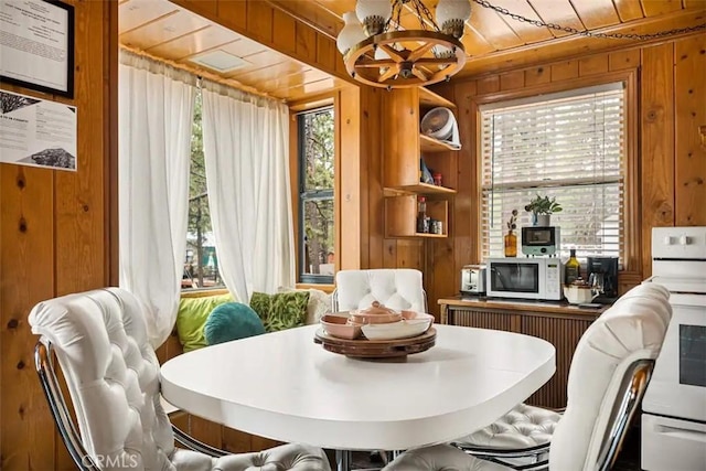 dining room featuring an inviting chandelier, wood ceiling, and wooden walls